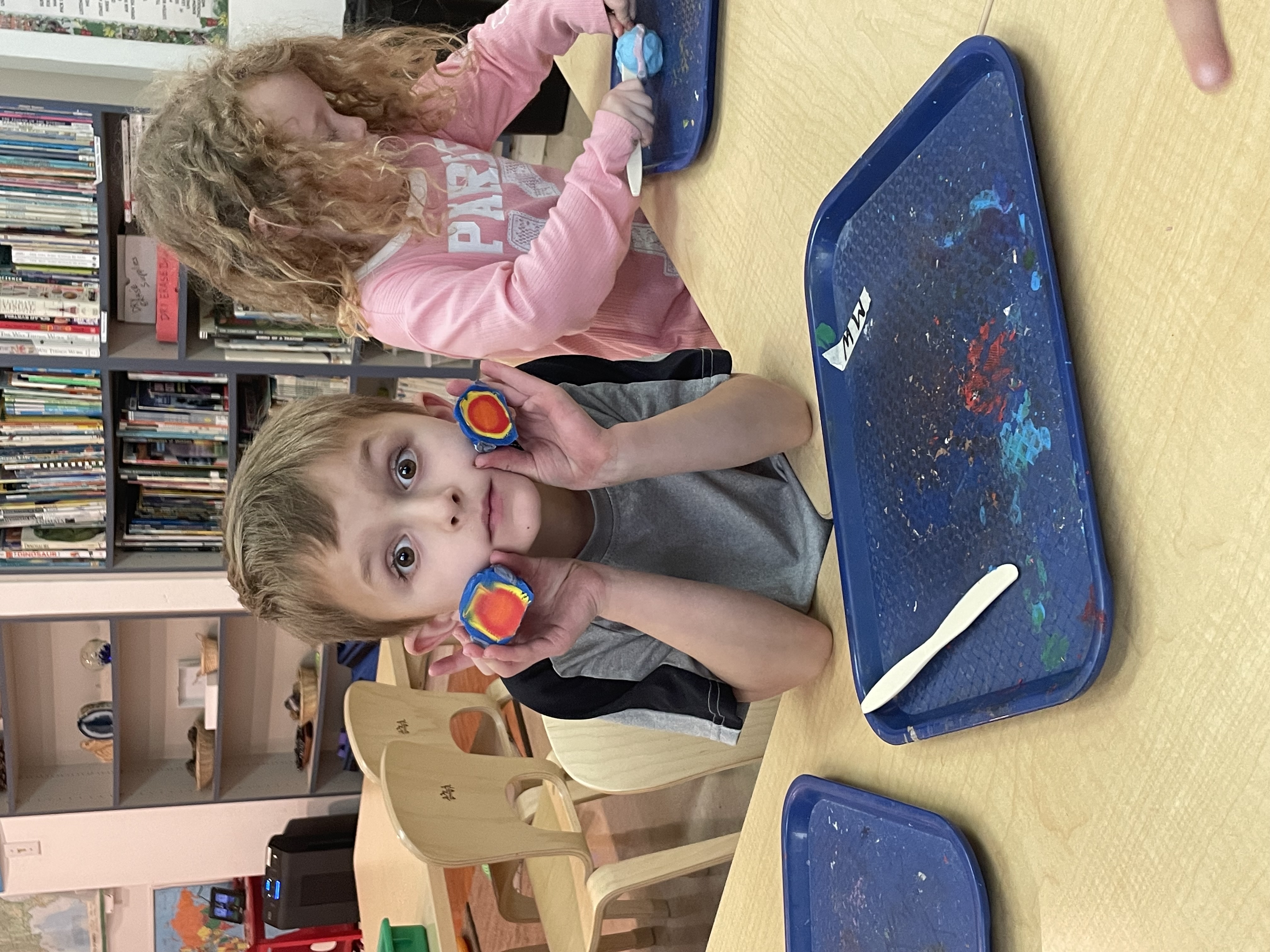 Early kindergarteners preparing vegetables together at a long table
